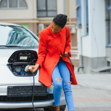 A lady in a red coat plugging in an EV