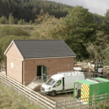 A building that is a substation with two vans parked outside in Byrness, Northumberland