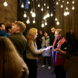 People stood inside Durham Cathedral underneath light bulbs